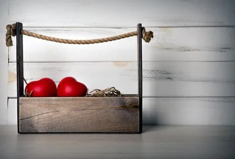Decorative basket with two large red hearts on a wooden background Stock Photos