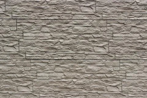 Decorative beige wall of artificial torn stone as a background or texture. Stock Photos