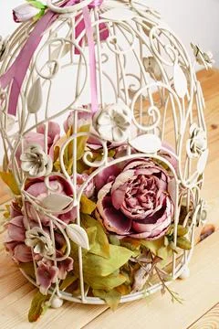 Decorative cage with a composition of artificial flowers. Stock Photos