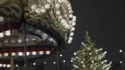 Decorative carousel lights illuminate Christmas tree in festive night scene 스톡 동영상 340267970