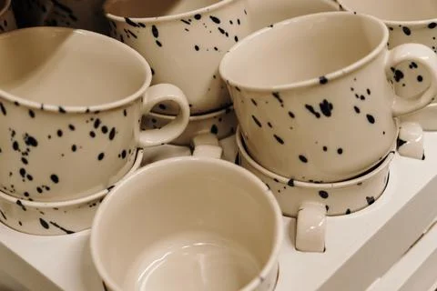 Decorative ceramic cups with black speckled pattern displayed in a home goods Foto stock