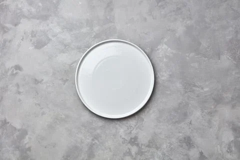 Decorative ceramic empty white handmade plate presented on a gray concrete .. Stock Photos
