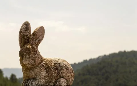 Decorative ceramic rabbit with an out-of-focus mountain image in the backgrou Stock Photos