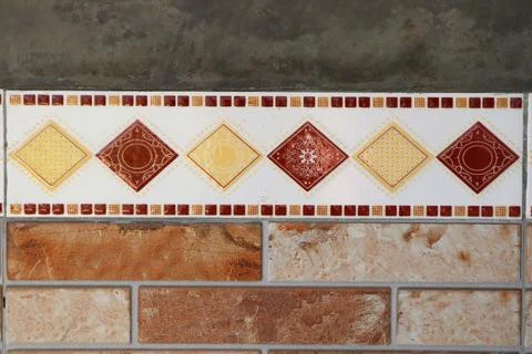 Decorative ceramic tile border with geometric diamond patterns separating a.. Stock Photos