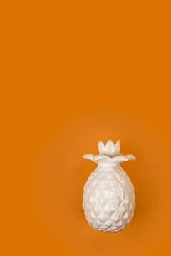 Decorative ceramic white pineapple on a bright orange background. Pineapple o Stock Photos