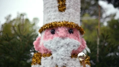 Decorative Christmas nutcracker soldier figure displayed outdoors with trees in Stock Footage 325800067