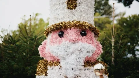 Decorative Christmas nutcracker soldier figure displayed outdoors with trees in Stock Footage 325803673