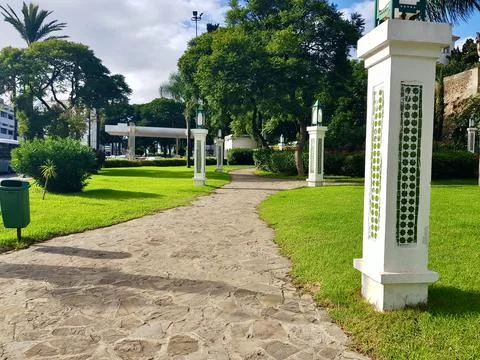 Decorative columns and a path between grass and greenery in the public park Stock Photos