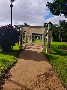 Decorative columns and the path between green spaces in the public garden Stock Photos