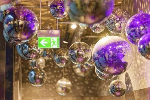 Decorative disco balls hanging from ceiling with illuminated emergency exit.. Stock Photos