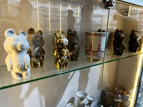 Decorative display of bear figurines and an Olympic cup on a glass shelf Stock Photos