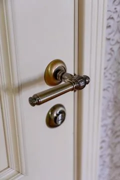 Decorative door handle and lock on a wooden door with intricate design Stock Photos