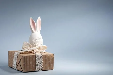 Decorative Easter bunny with a gift box on a light blue background Stock Photos