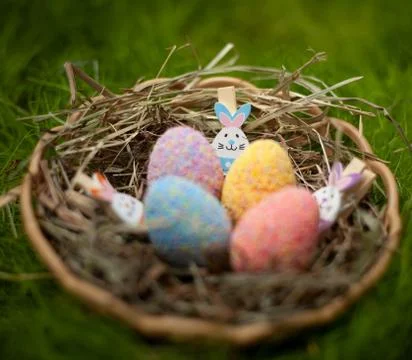 Decorative Easter colored eggs in a basket with hay decorated with Easter rab Stock Photos