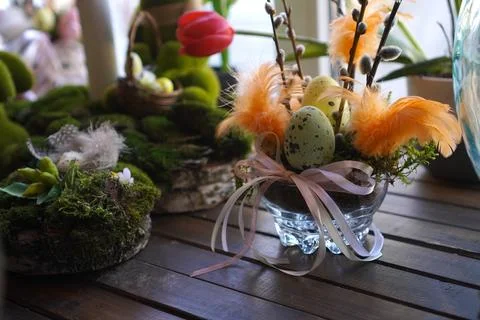 Decorative Easter display featuring speckled eggs, orange feathers, and pus.. Fotos de archivo