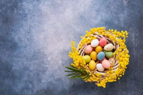 Decorative Easter eggs in mimosa wreath on a bright blue background. Top view Foto stock