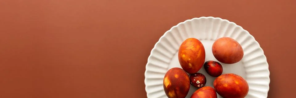 Decorative Easter eggs in various shades of red and orange sit on a white pla Stock Photos