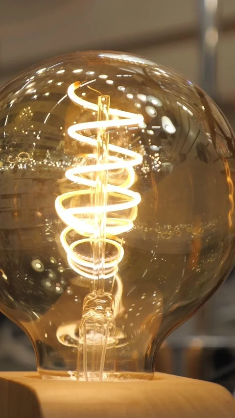 Decorative edison light bulb with a glowing spiral filament creating a warm and Stock Footage 341678505