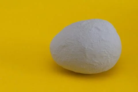 Decorative egg covered with gray plaster on a yellow background. Stock Photos