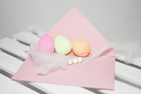 Decorative eggs with a feather on a pink envelope Stock Photos