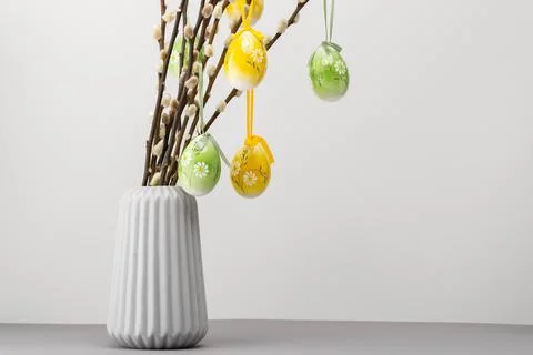 Decorative eggs hang from branches in a simple vase on a gray table in a ho.. Stock Photos