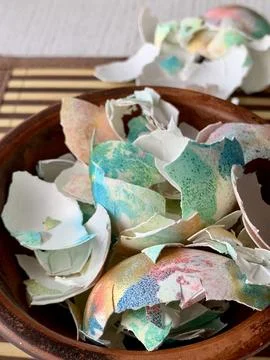 Decorative eggshells of various colors and patterns rest in a wooden bowl, Stock Photos