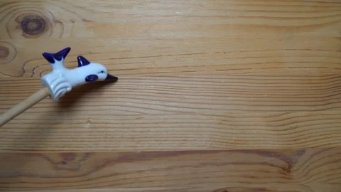 Decorative element - ceramic shape of dolphin moving on wooden background Stock Footage 93073508