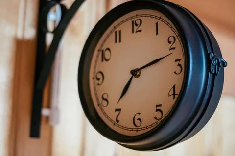 Decorative elements. Round vintage clock in black metal hanging on corner m.. Stock Photos