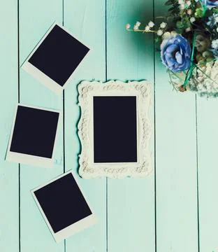 Decorative empty photo frame and blank polaroids on a teal wooden surface with a Stock Photos