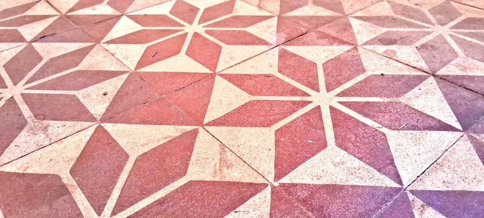 Decorative floor tiles featuring repeating geometric star patterns in red hues Stock Photos