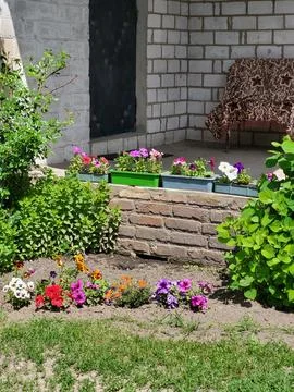 Decorative flower bed by a light brick wall, residential yard landscape design Fotos de archivo
