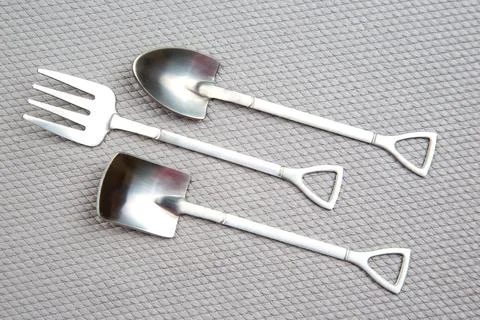 Decorative fork and spoons in the form of spades on a gray background. food.. Stock Photos