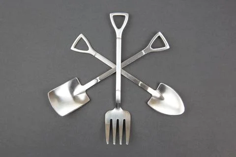 Decorative fork and spoons in the form of spades on a gray background. food.. Stock Photos