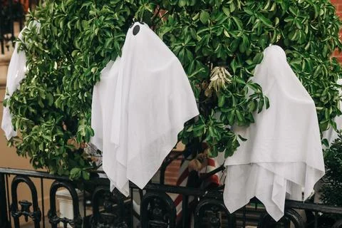 Decorative ghosts hanging on a tree outside a house for Halloween celebration Stock Photos