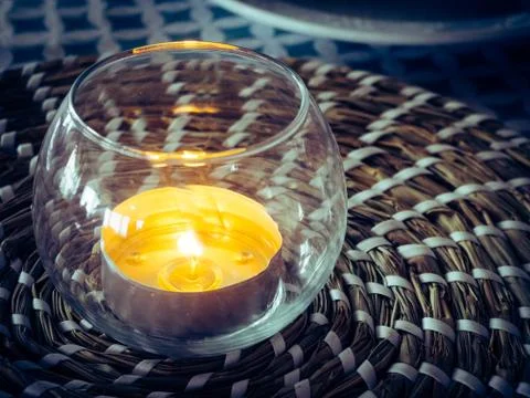 Decorative glass with a burning candle inside on a table, home interior decor Stock Photos