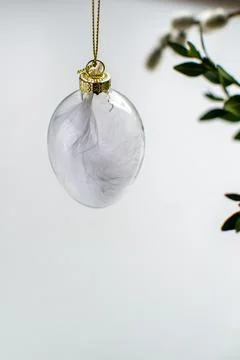 Decorative glass Easter egg with white feather inside Stock Photos