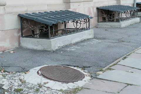 Decorative Grate Over a Basement Window on a Paved Streetside Stock Photos