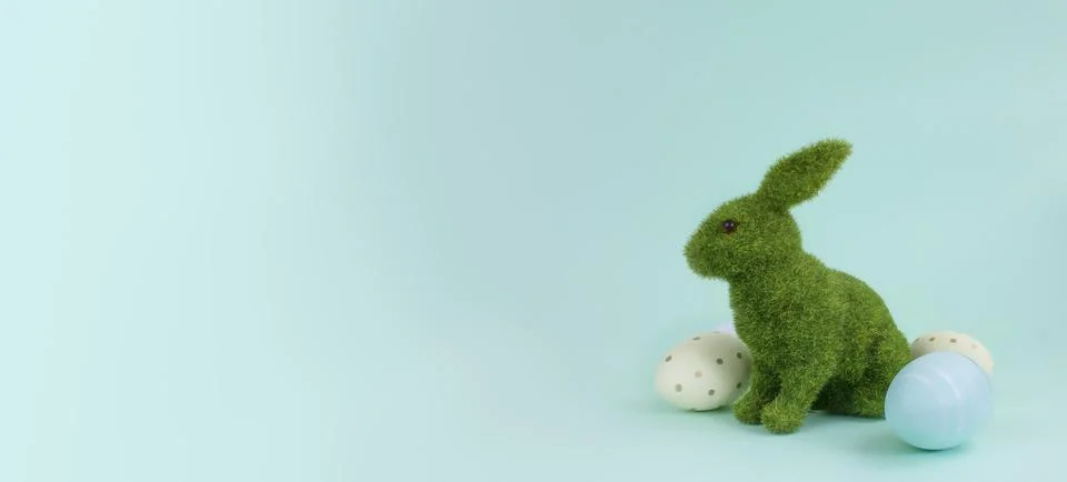 Decorative green rabbit and Easter eggs on a blue background, copy space. Stock Photos