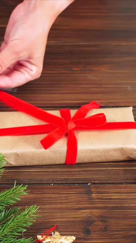 Decorative handwrapped holiday package, Closeup of hands tying festive ribbon on Stock Footage 322508283