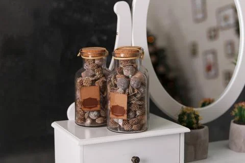 Decorative jars with dry nuts decorate a room interior Stock Photos