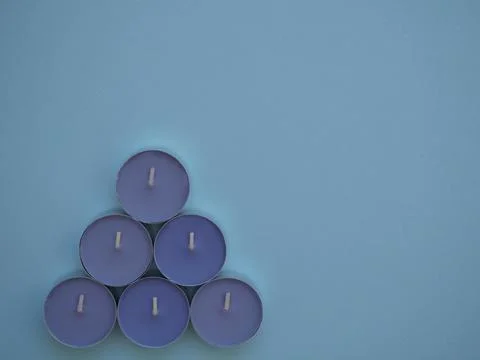 Decorative lavender candles in triangle shape on blue background with copy space Stock Photos