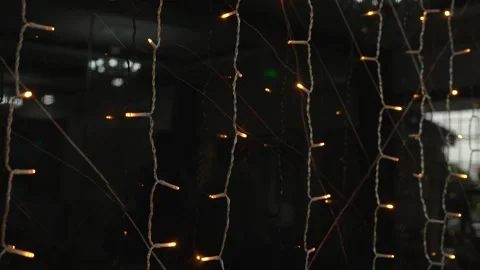 Decorative lights hang on strings in a dark space during the evening hours at a Video stock 334012720