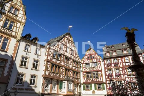 Decorative medieval buildings in village square with silhouette of angel fountai Stock Photos
