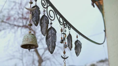 Decorative metal leaf feathers and bells swaying in wind outdoors Stock Footage 268603802