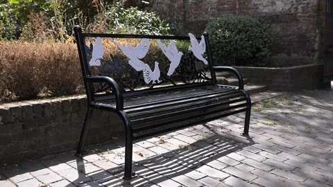 Decorative Metal Park Bench With Bird Silhouette Backrest in Sunlit Garden Video stock 345010426