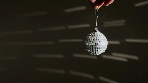 Decorative mirror ball with silvery reflections rotating on a dark background. Видео 256953262