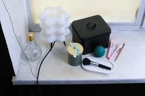 Decorative objects and makeup brushes arranged on a marble windowsill Stock Photos