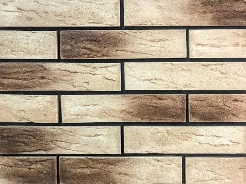 Decorative panel in the form of a beige and brown old brick. Stock Photos