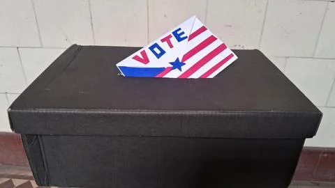 Decorative paper ballot placed inside black cardboard election box for voting Foto stock