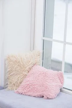 Decorative pillows with long pile pillowcases lie on the windowsill Stock Photos